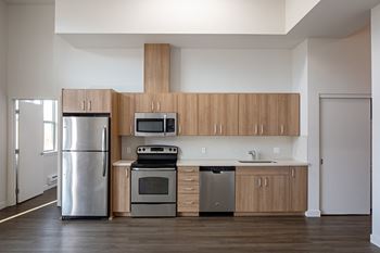 an empty kitchen with stainless steel appliances and wooden cabinets